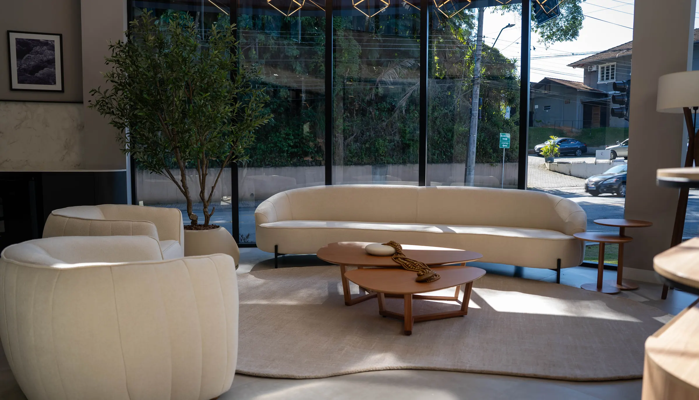 Lounge entregue pela RAK Engenharia, com sofá curvo, mesa de centro e parede envidraçada